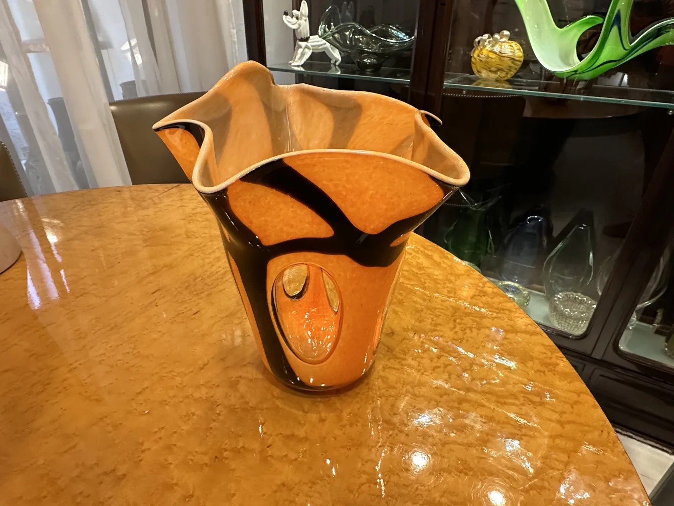 antique vase with wide base and elegant curves, in orange and black color, on wooden table