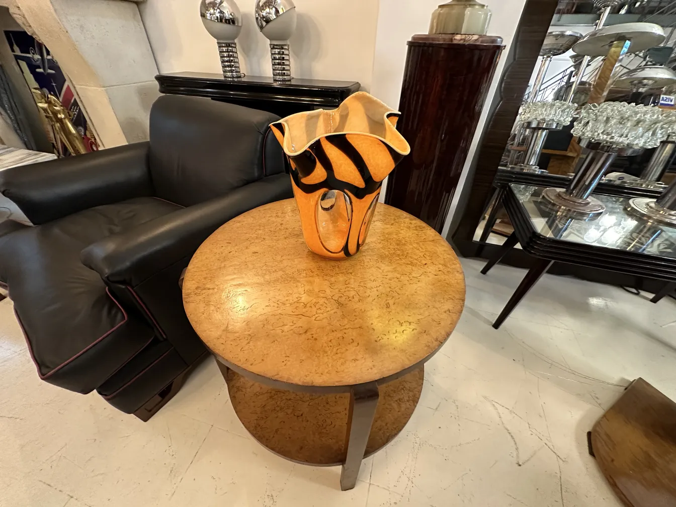 vaso antigo laranja com design preto, em mesa de madeira, sofá preto ao fundo