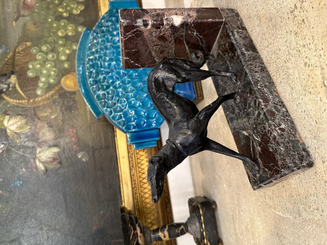 Antique bookends shaped like a black dog on a marble base, surrounded by vibrant décor.