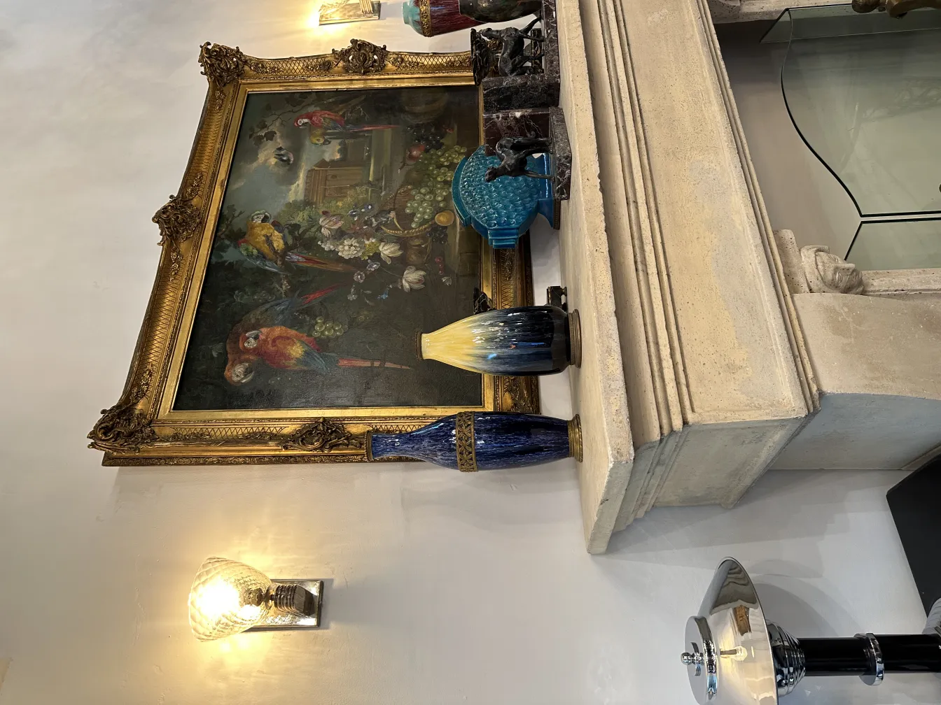 エレガントなデザインの古代装飾ブックエンドが色とりどりの絵画や他の装飾品の横にあります。