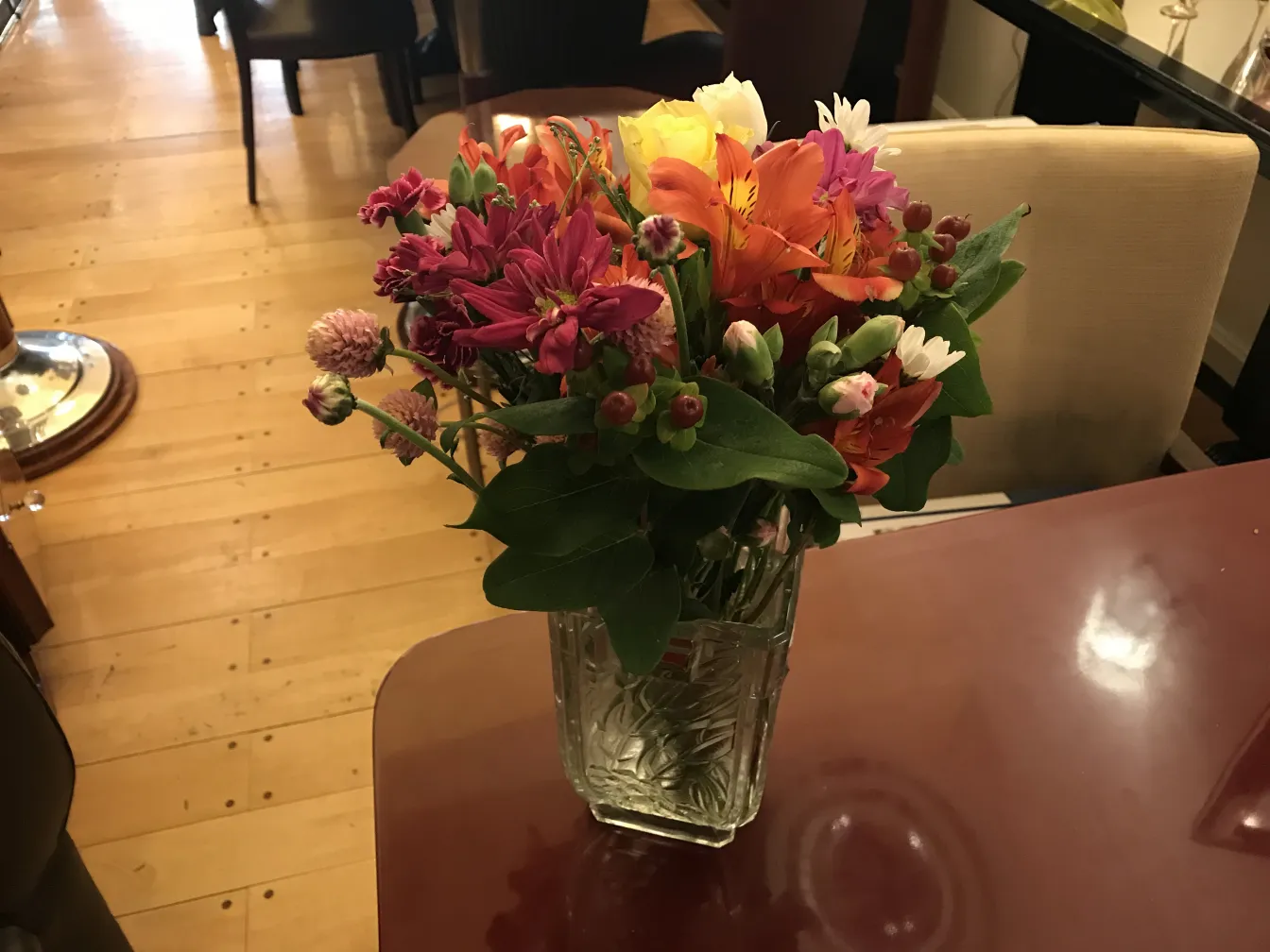 florero antiguo lleno de flores coloridas sobre una mesa