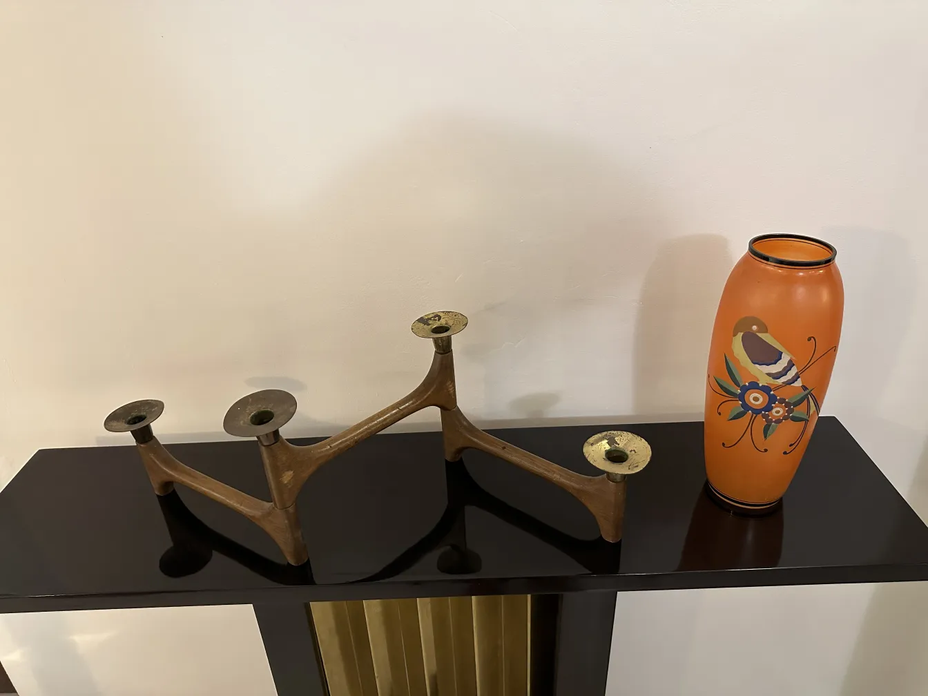 vaso antico arancione decorato con motivi colorati, accanto a un candelabro