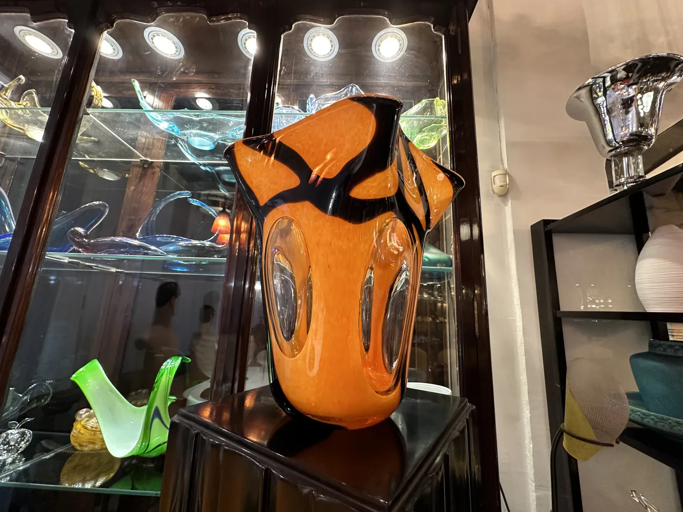 vase antique orange avec détails noirs, exposé dans une vitrine