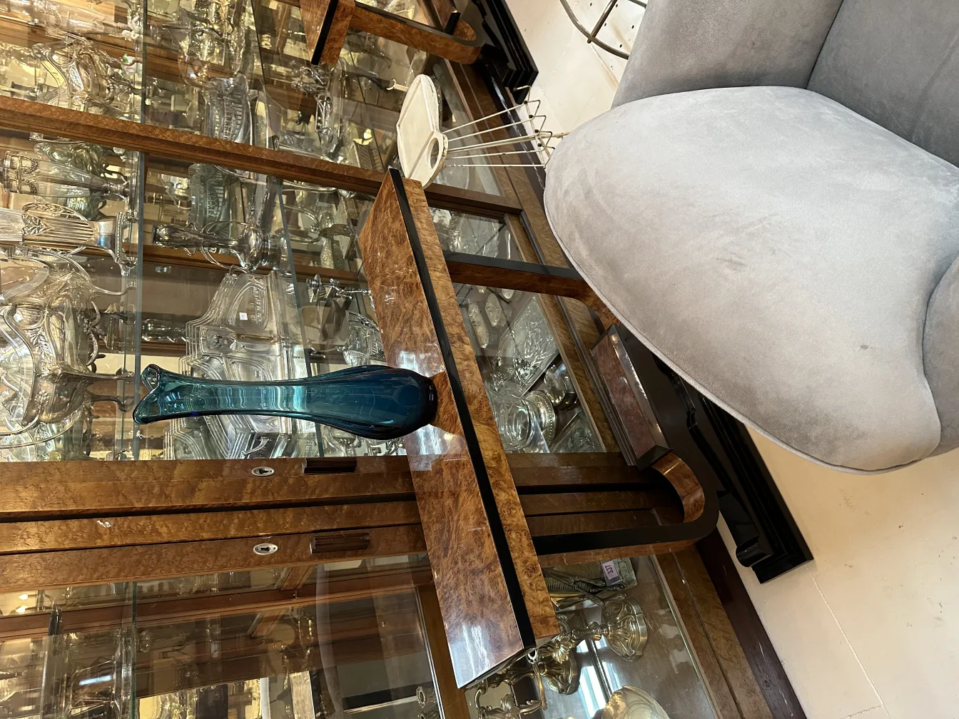 Vaso antigo azul sobre mesa, com fundo de cristaleira