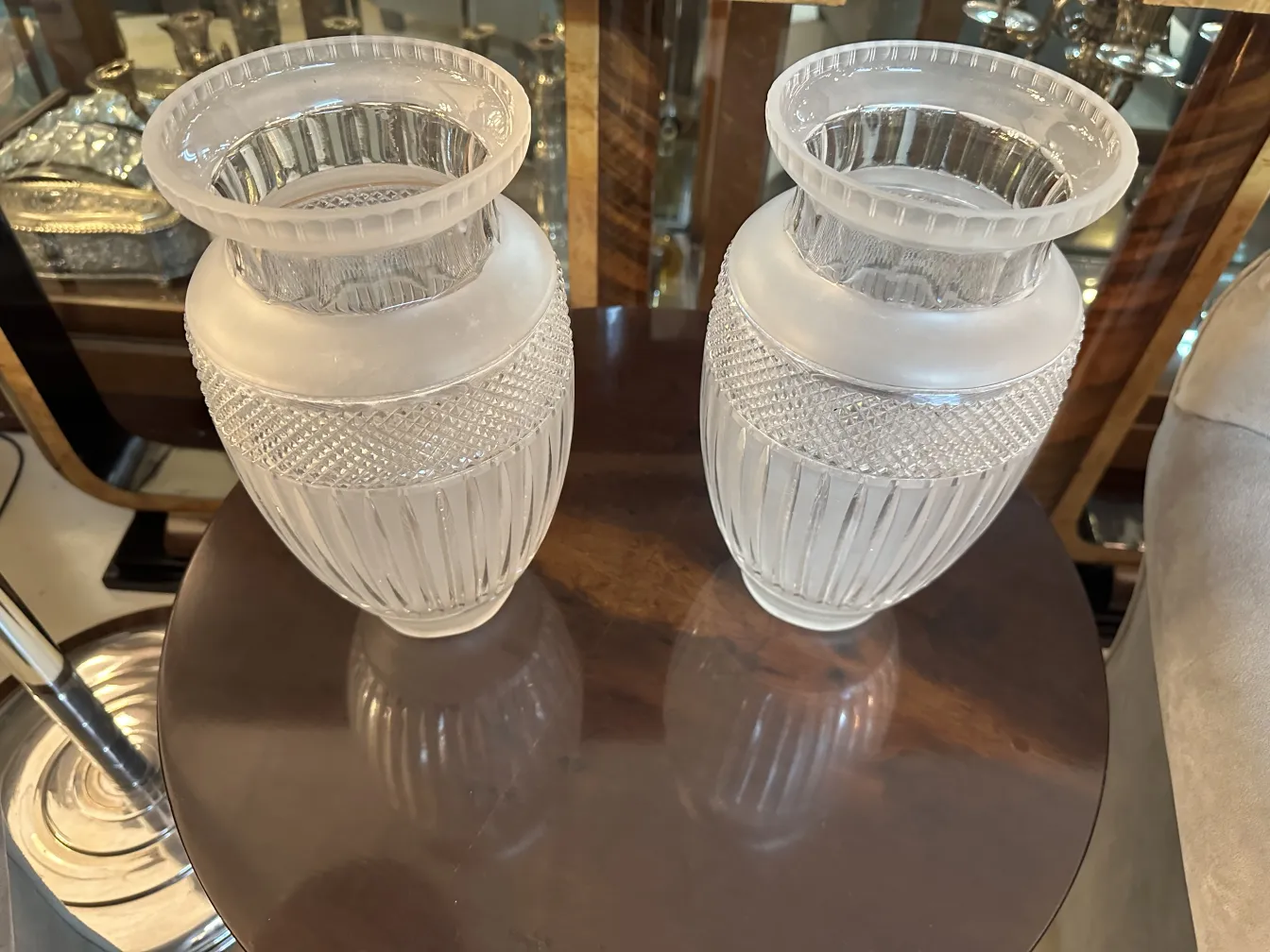 deux vases anciens avec des détails décoratifs en haut, sur une table élégante