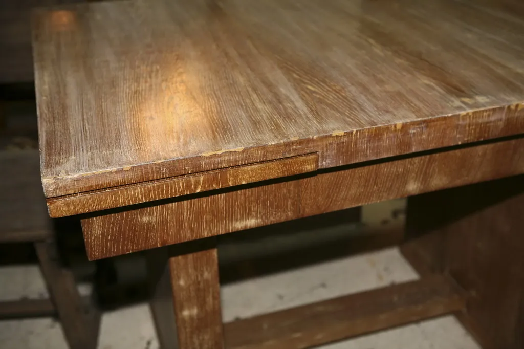 Descripción de mesa de comedor antigua con acabado claro, diseñada por Jean Michel Frank, ideal para 6 o 4 personas, en un ambiente acogedor.