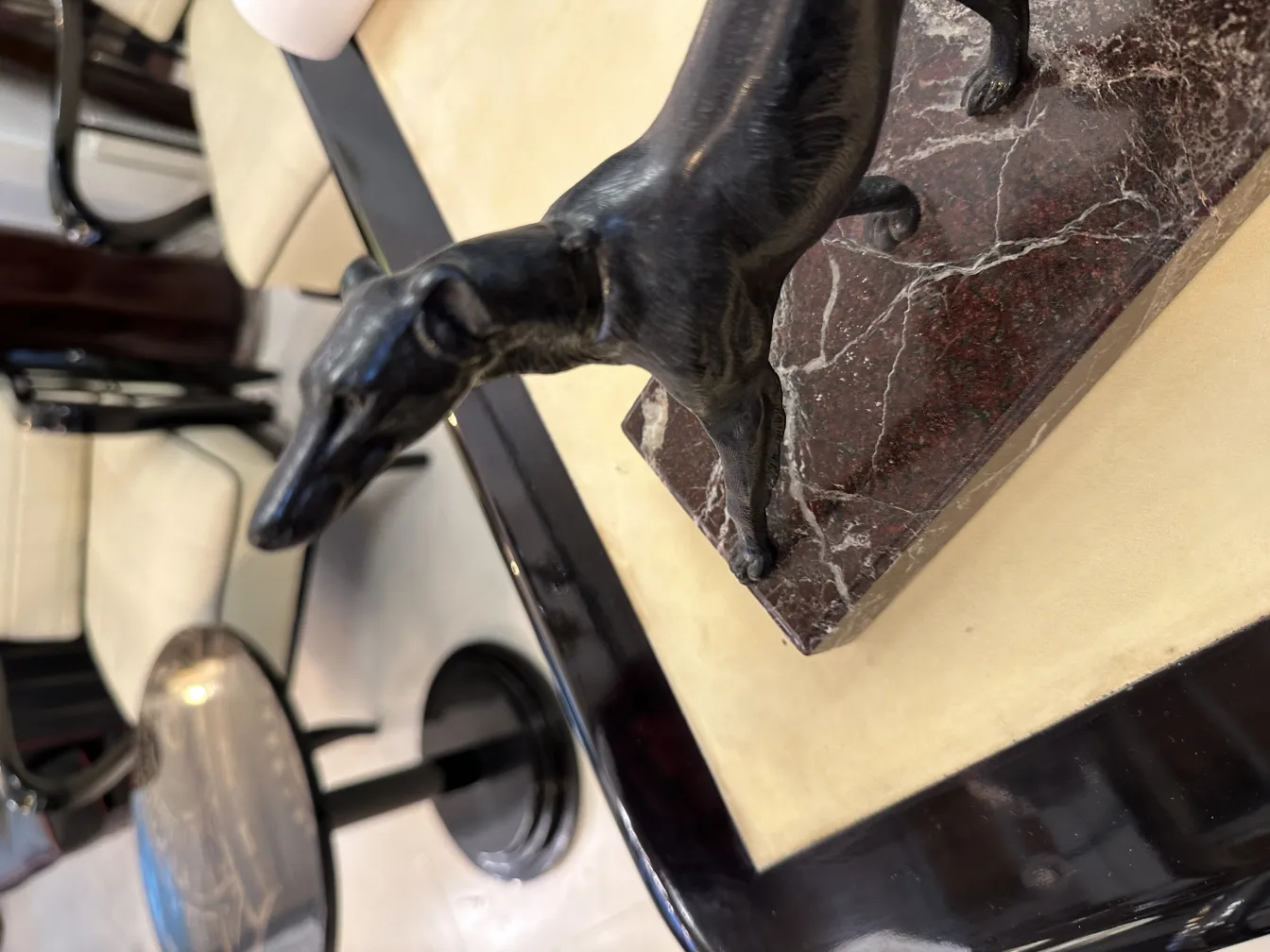 Antigo suporte para livros em forma de cachorro de bronze, sobre uma superfície de mármore.