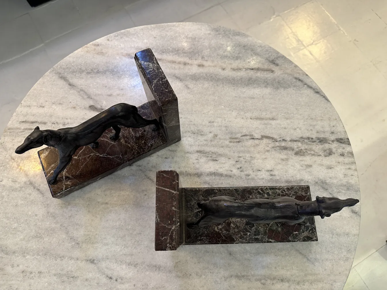 Antique bookends featuring hunting dog figures, elegant and decorative, on a marble table.