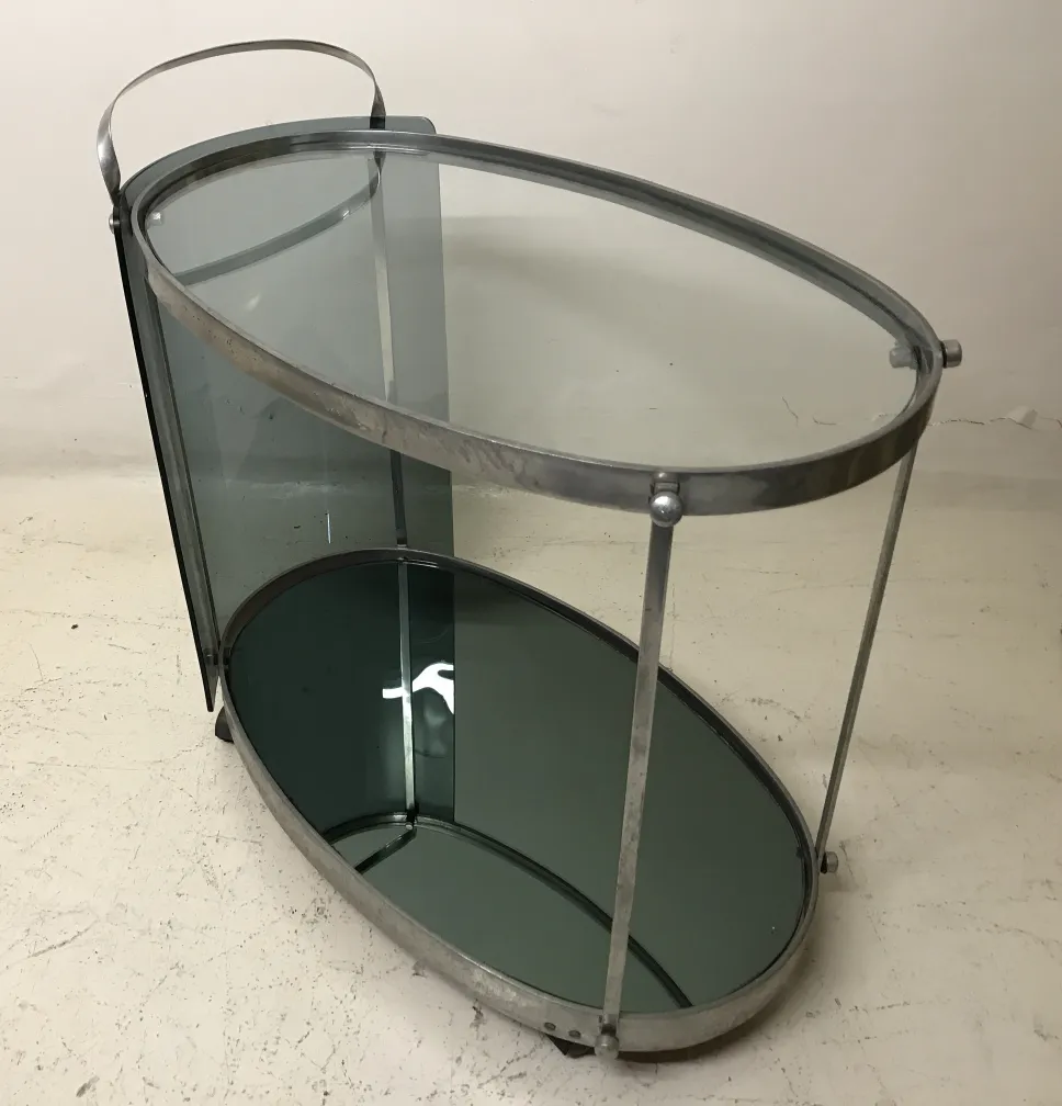 Antique cocktail trolley with oval shape and two shelves in a minimalist setting.