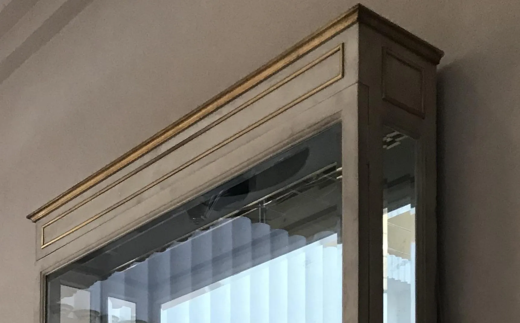 vitrine ancienne avec des détails décoratifs en haut, dans un environnement prévu pour des expositions.