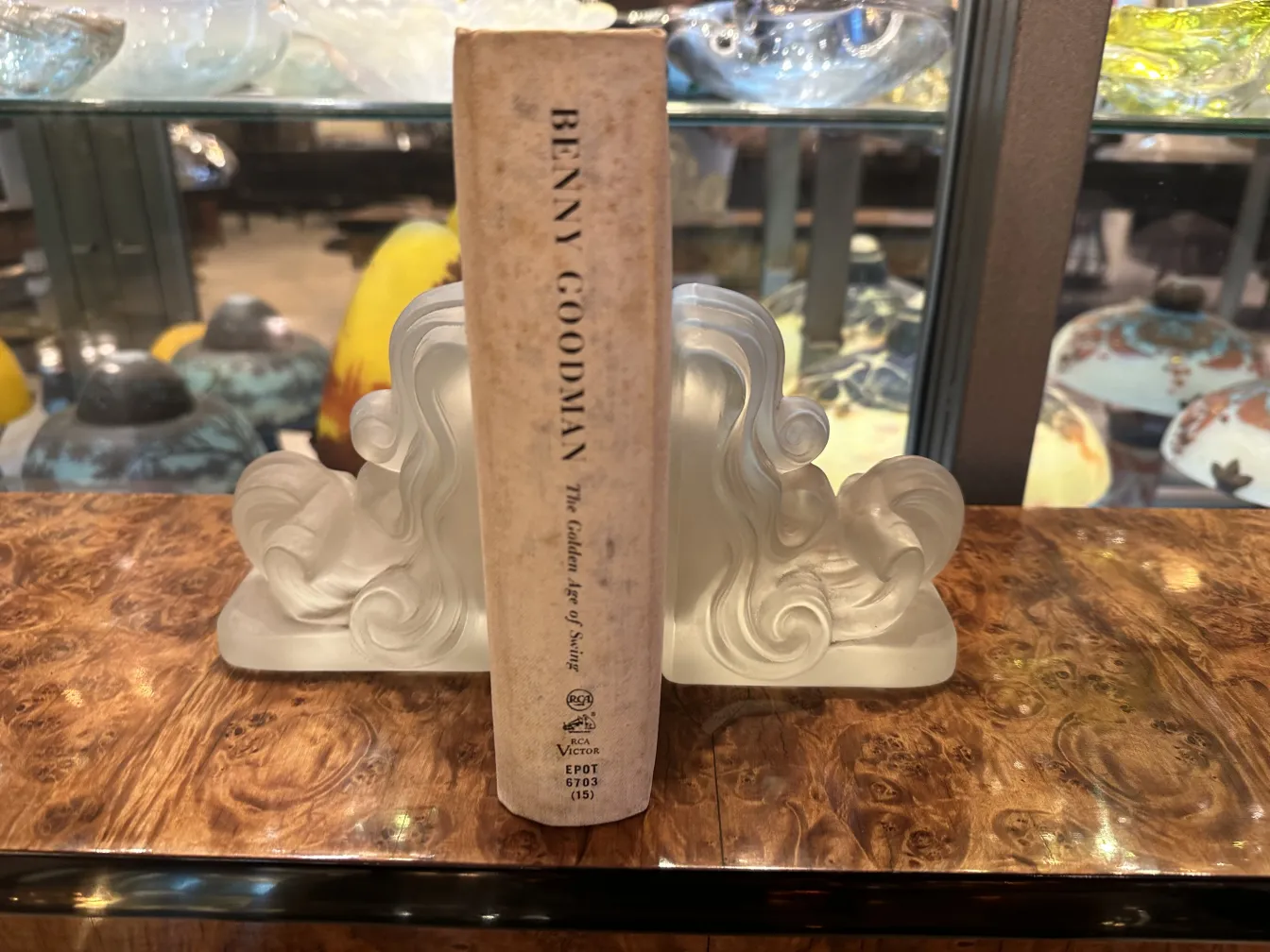 Antike Buchstützen mit elegantem Wellen-Design, das ein Buch auf einem Holztisch hält