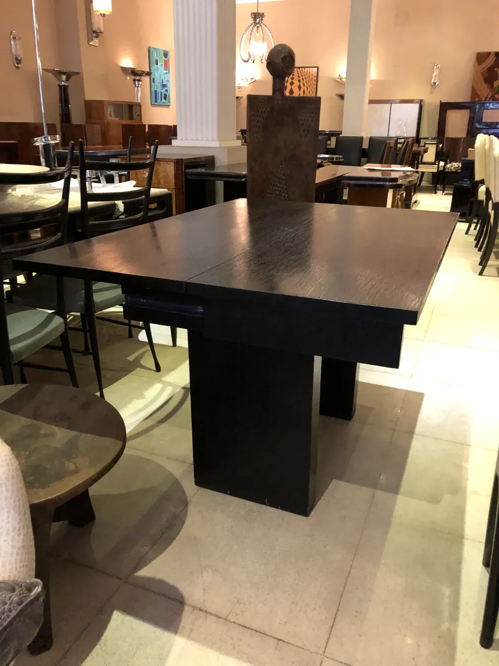 Antigua consola de muebles, con forma elegante y tonos oscuros, decorada con un objeto artístico en la parte superior.