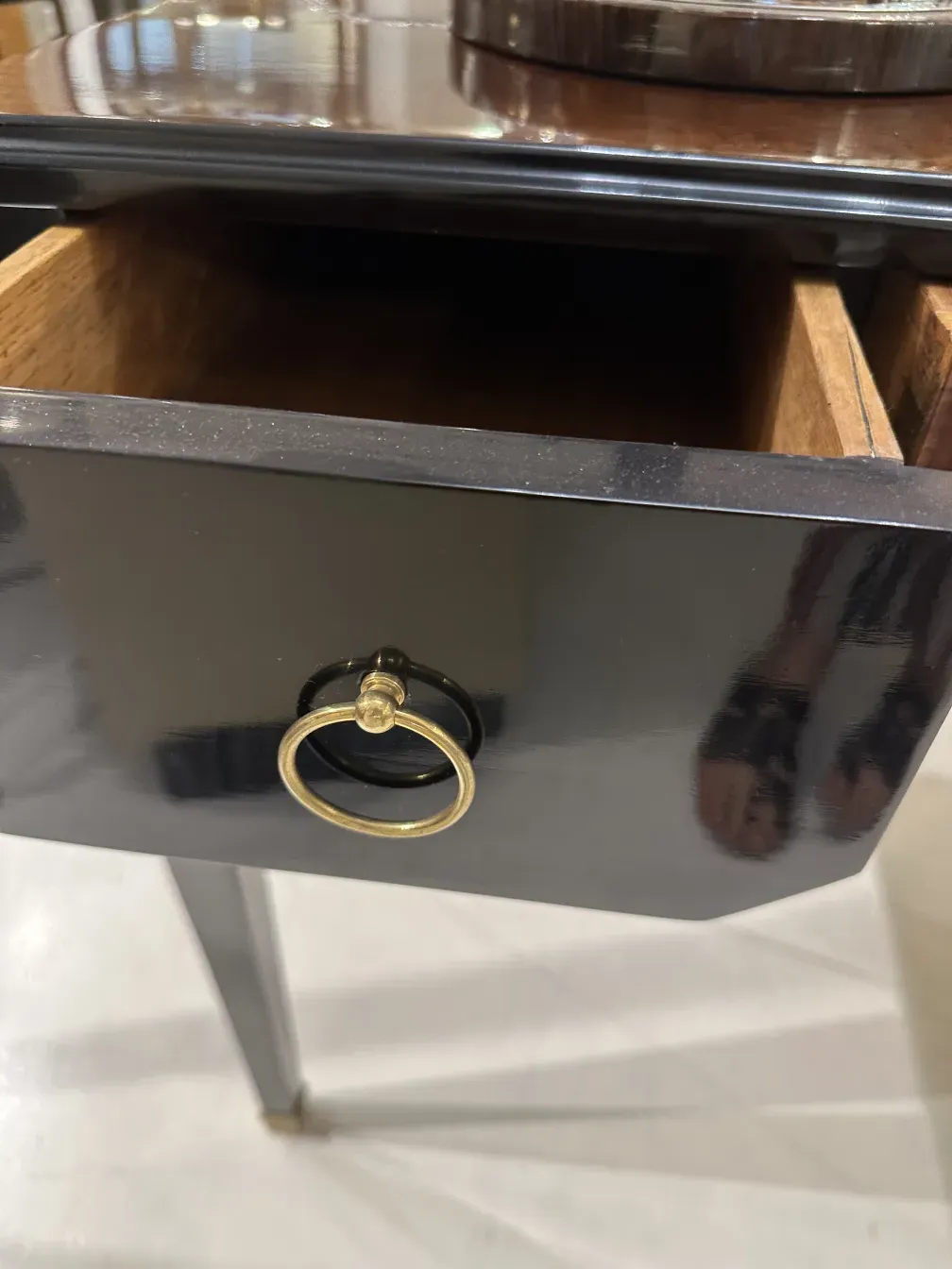 Escritorio antiguo con un acabado negro brillante y un tirador dorado. Ambiente elegante.