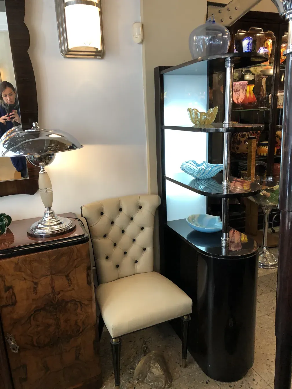 Antiquität Bar mit farbigen Glasobjekten und einem weißen Stuhl.