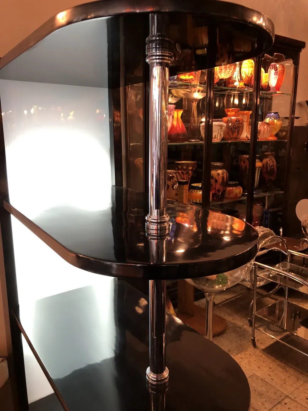 Antique bar cabinet with dark mirror and light background, decorated with colorful glass cups.