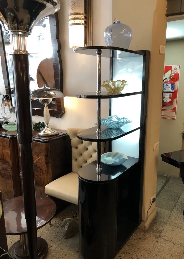 Mueble bar antiguo con estantes decorativos y lámpara.