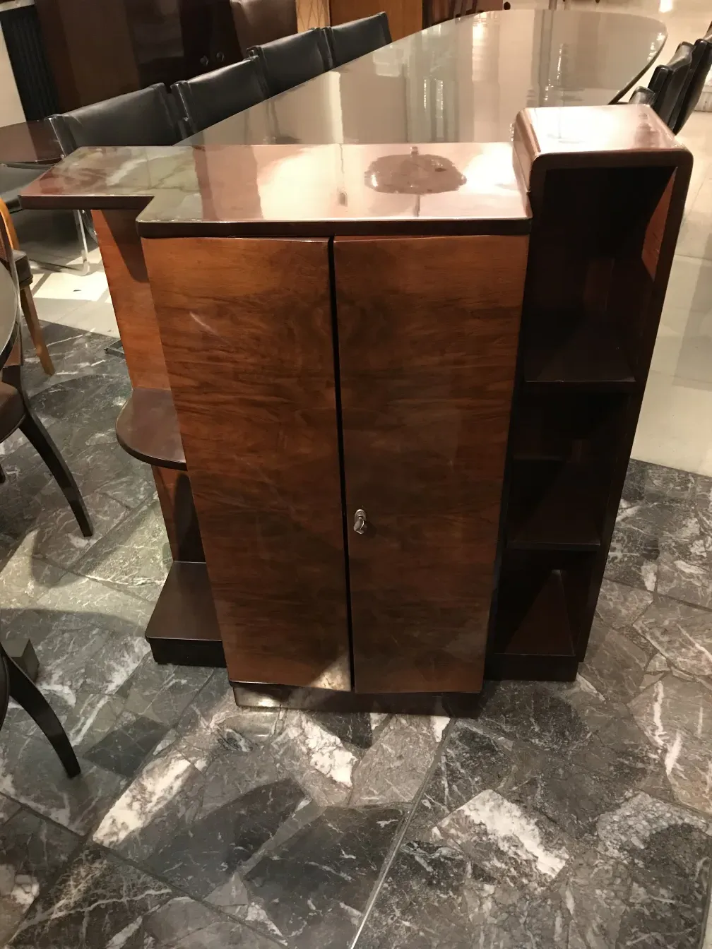 Античный книжный шкаф с блестящей отделкой и видимыми полками в элегантной обстановке.