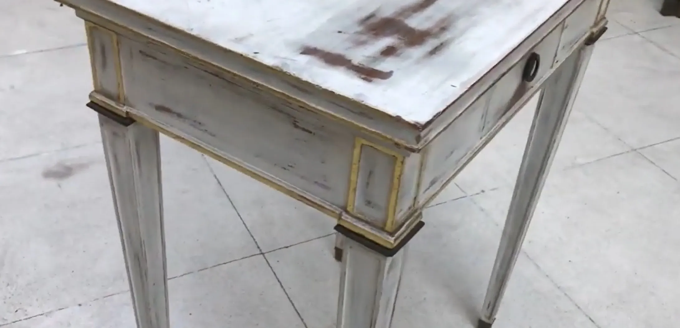 antik-weißer-schreibtisch-mit-goldenen-details-in-einem-neutralen-umfeld