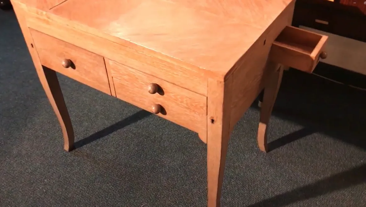 escritorio antiguo de madera clara con dos gavetas, en fondo azul