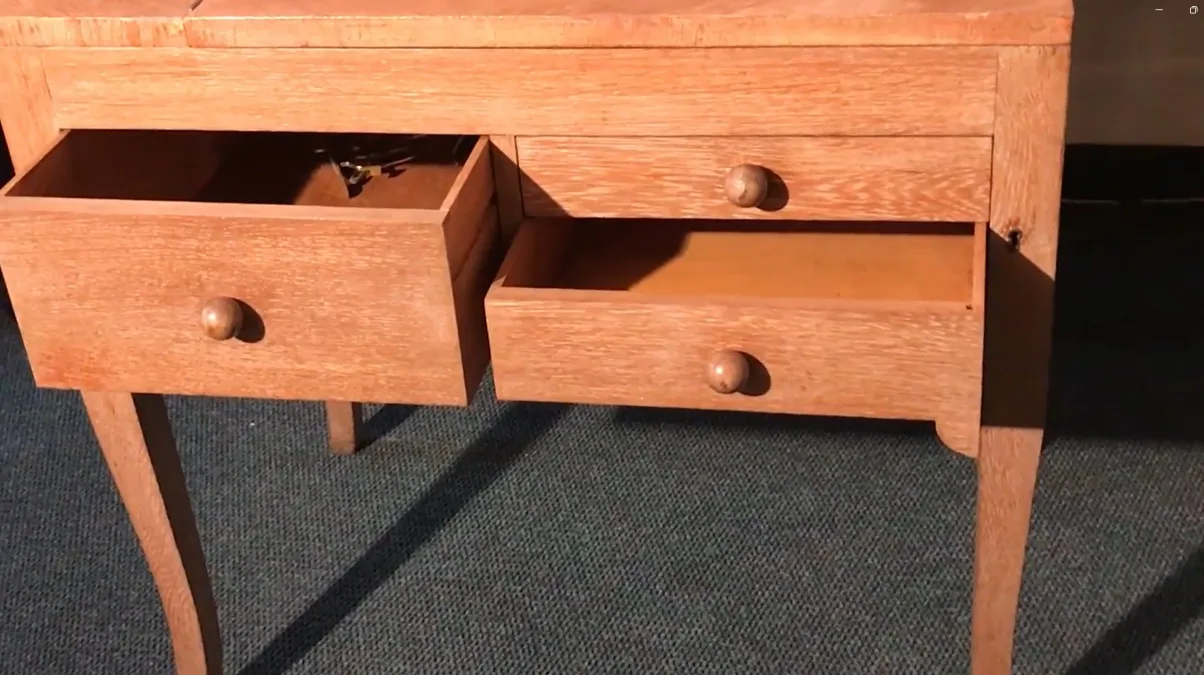 Antiker Holztisch mit zwei offenen Schubladen und schlanken Beinen.