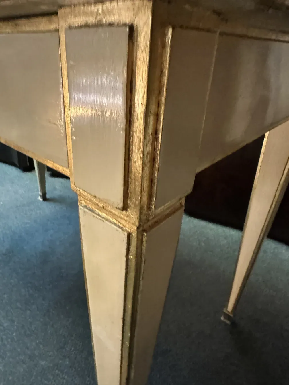 antiker Schreibtisch mit goldenen Details auf einem blauen Teppich