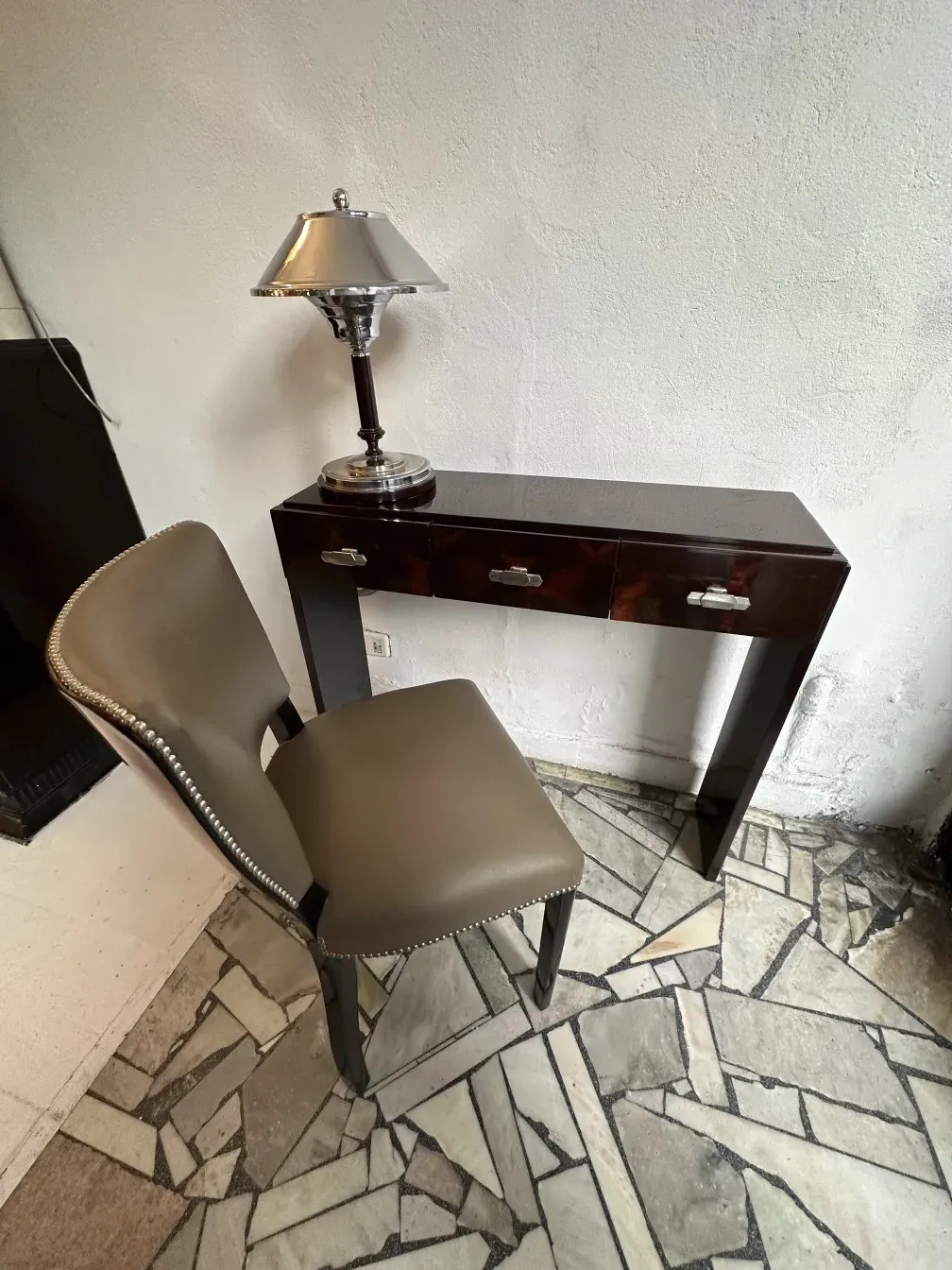 Two antique consoles in a modern design setting with a lamp and chair.