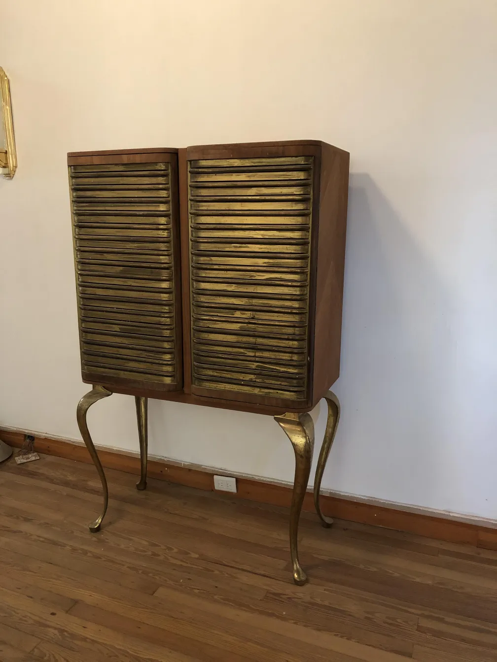 Antiker Holzbar mit goldenen Türen und eleganten Beinen.