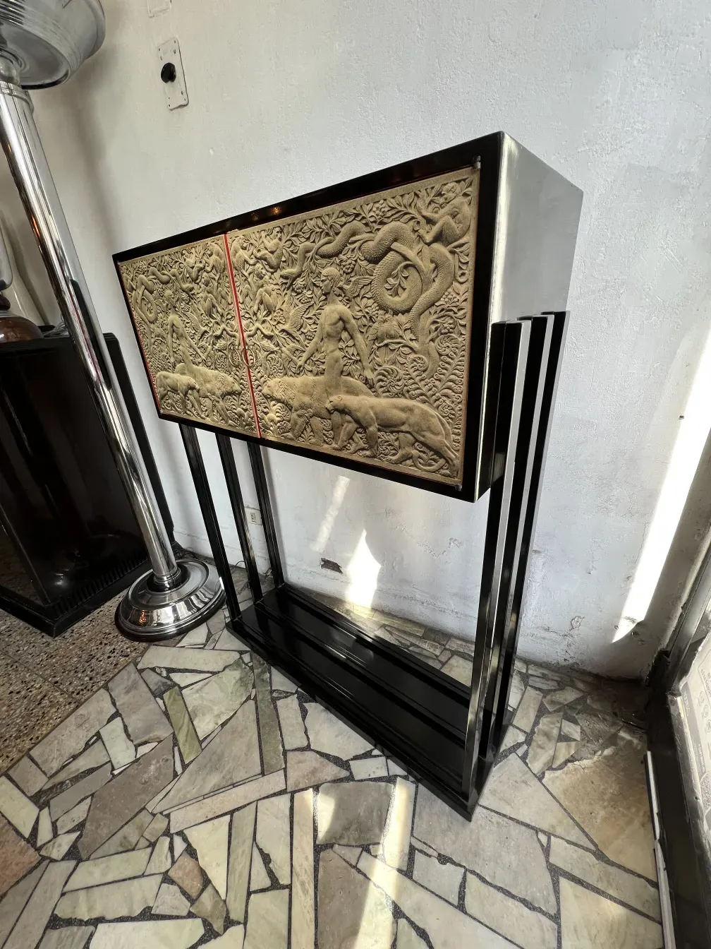 Mueble bar antiguo con arte en relieve en la parte superior.