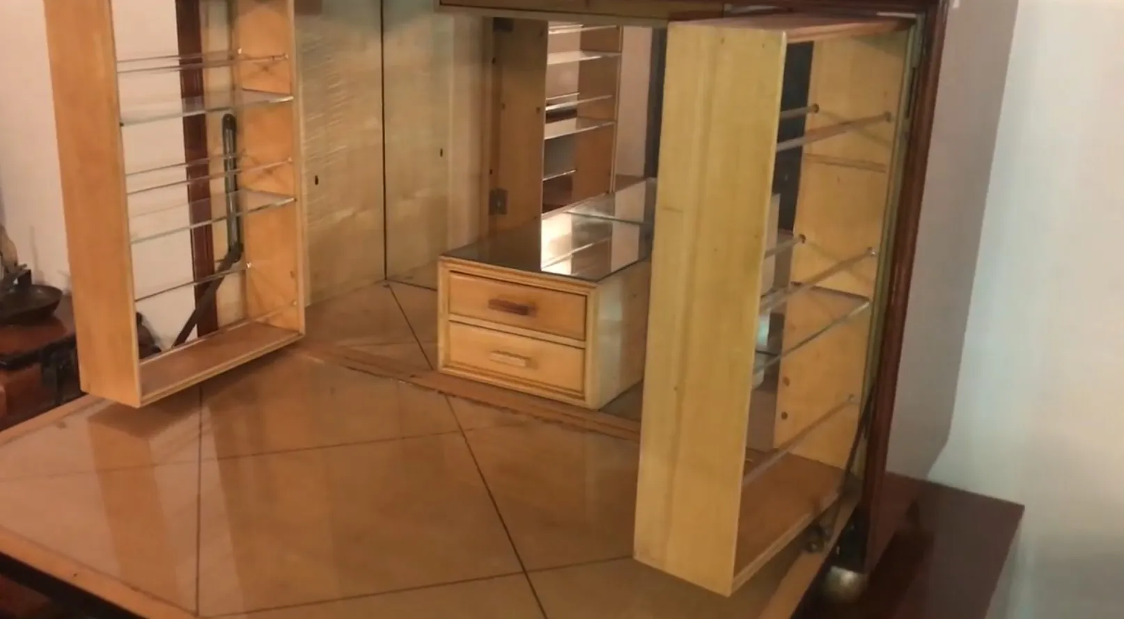 Mobile bar antico in legno con mensole e cassetto, in un'atmosfera accogliente in stile vintage.