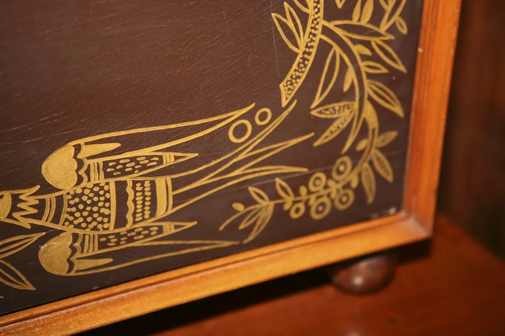 Meuble à cocktail antique avec un design floral doré sur fond sombre.