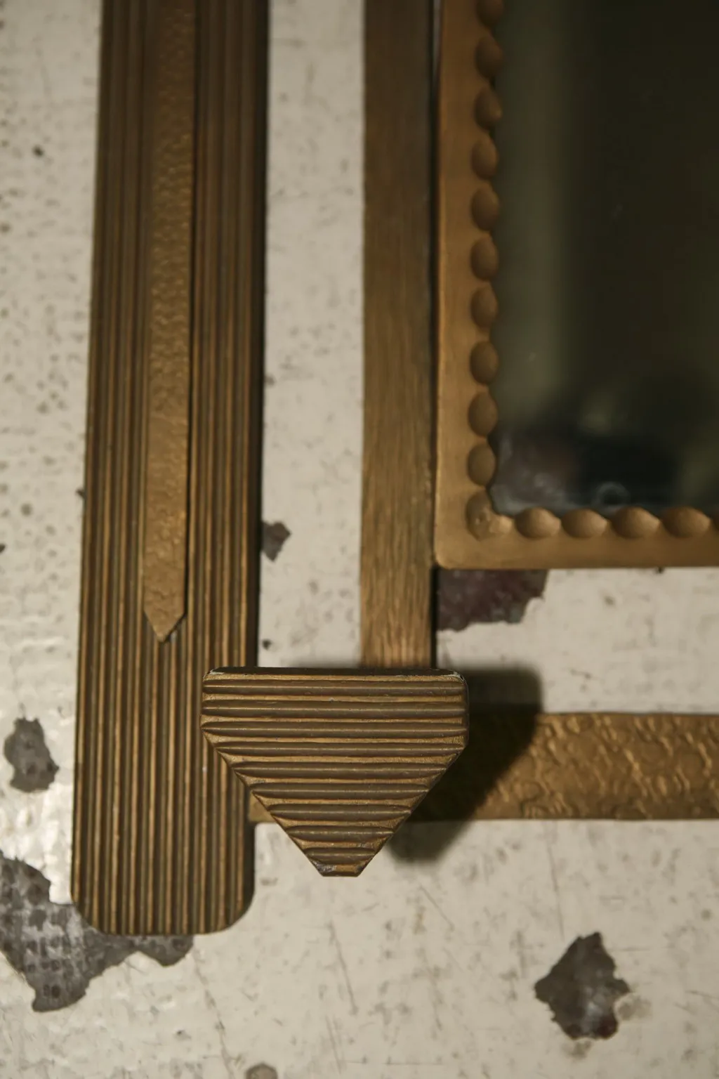 Antique coat rack with ridged gold patterns against a neutral background