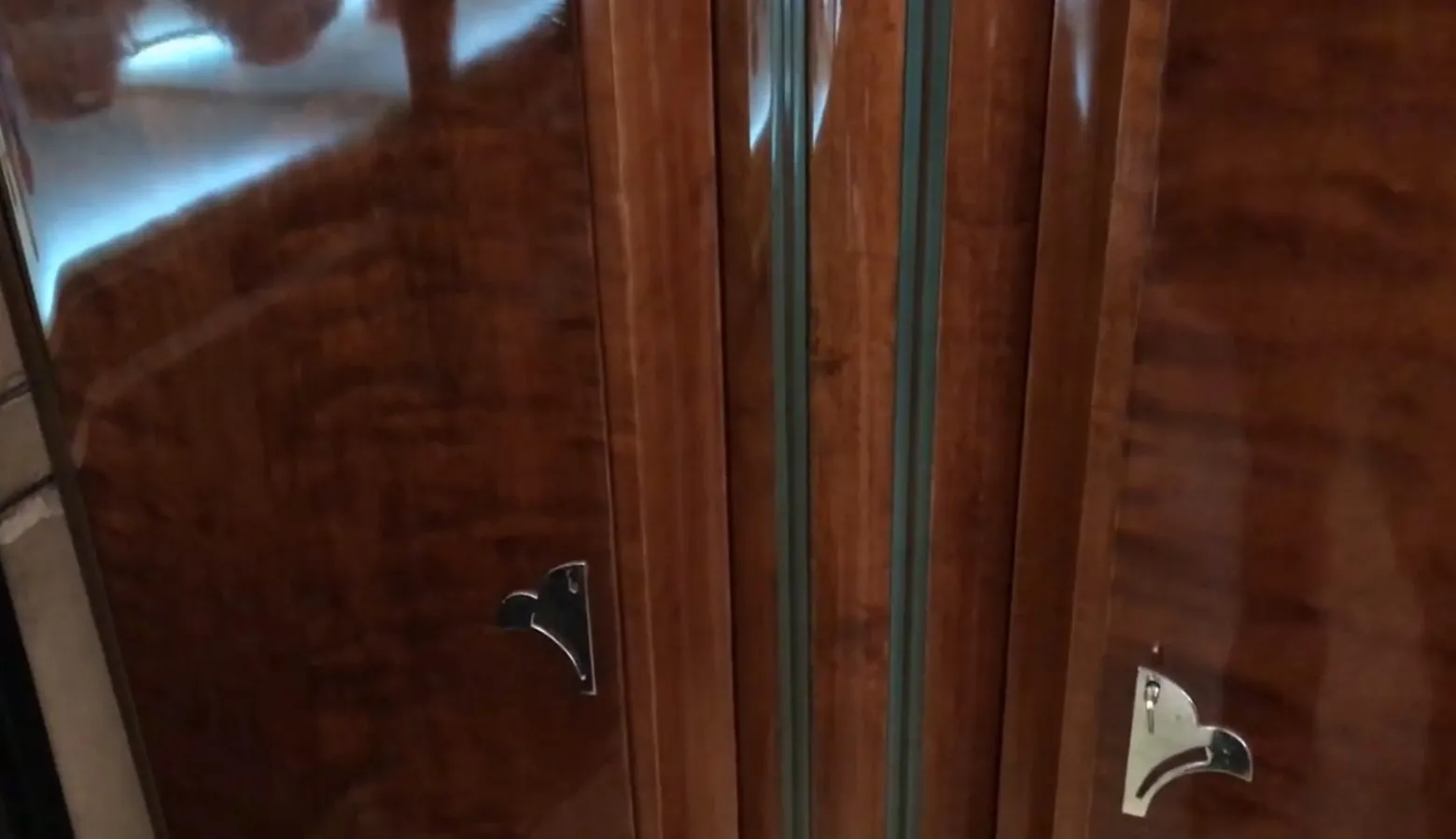 Antiga estante de livros com portas e detalhes em madeira polida.