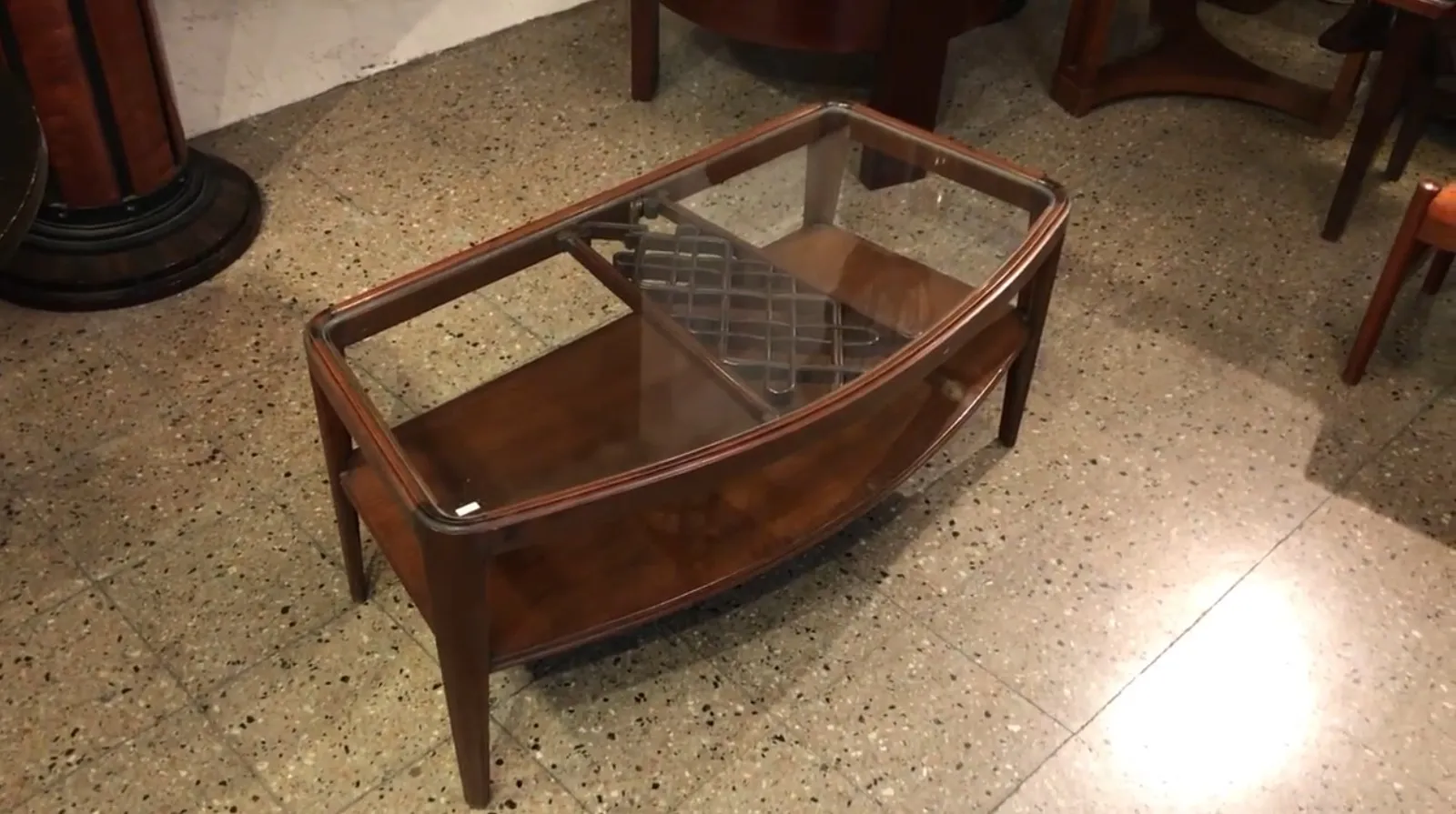 Mesa ratona antigua con vidrio y forma elíptica en un ambiente acogedor.