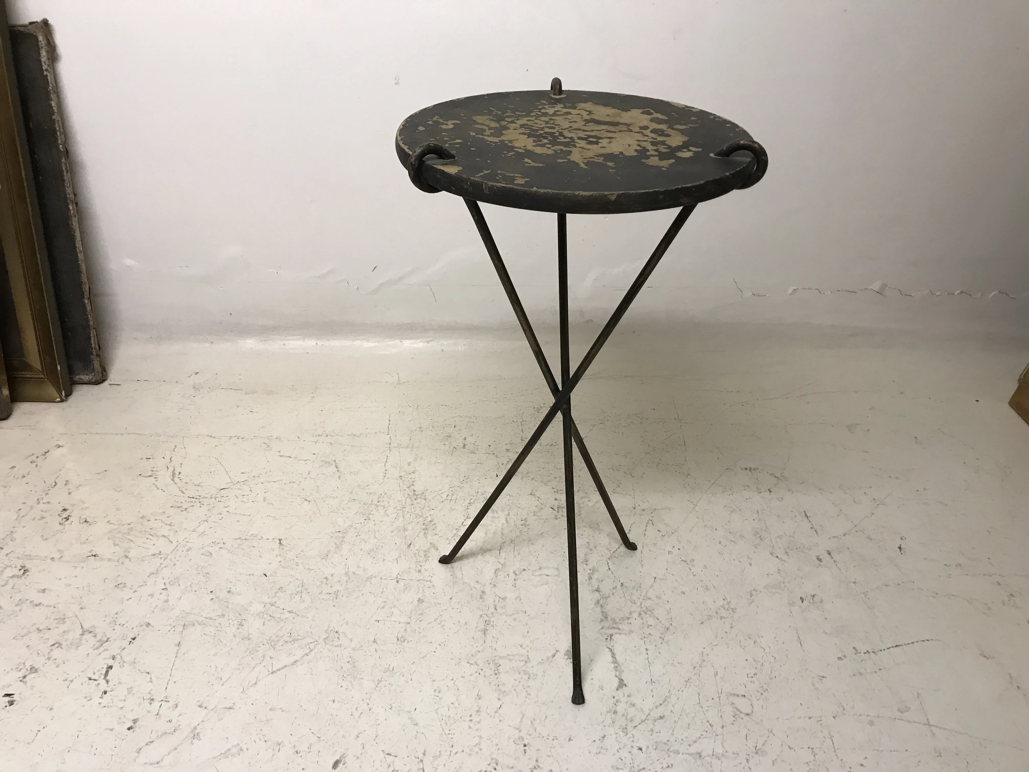 Antique folding small table with worn surface and crossed legs.