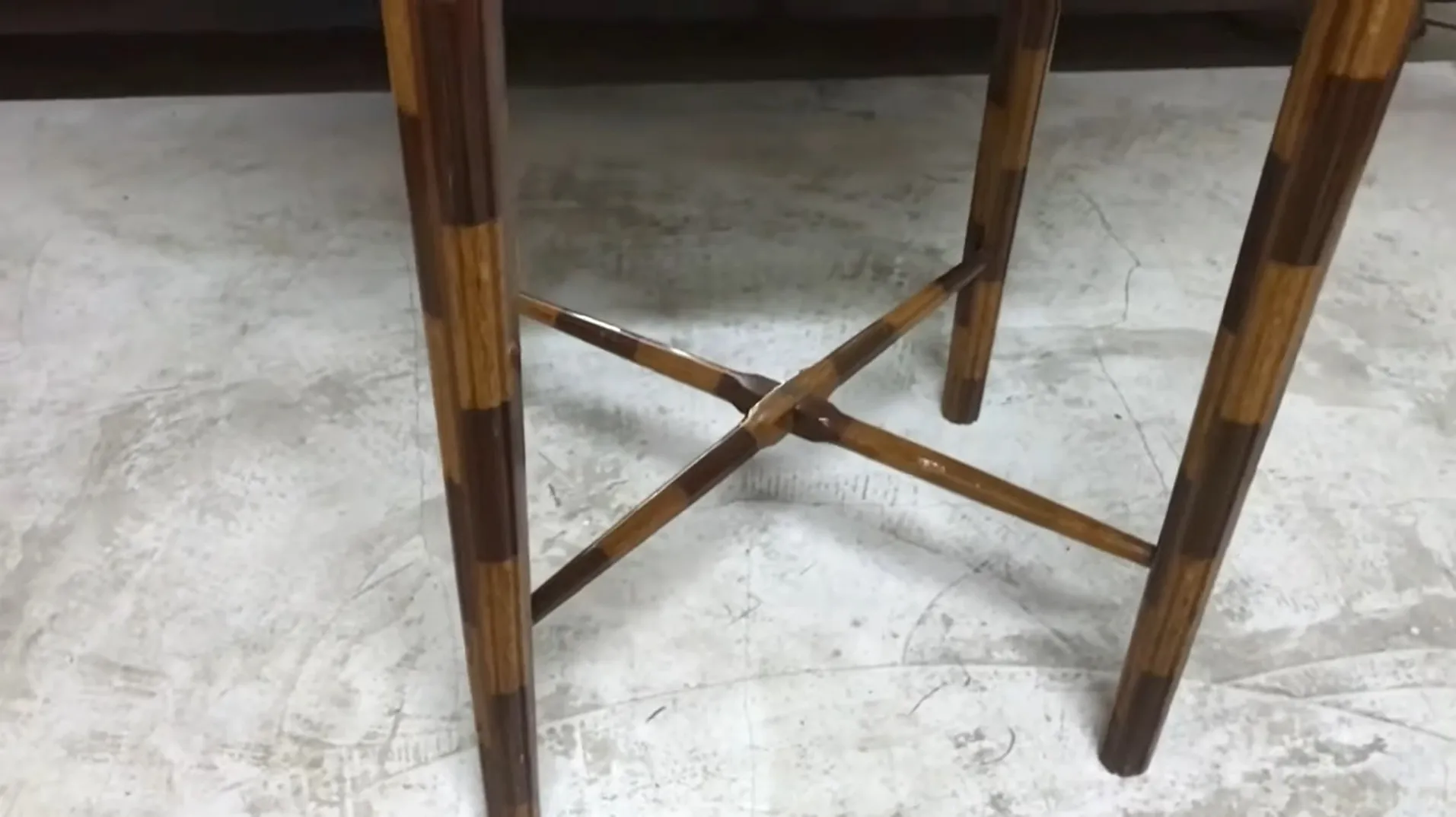 side view of an antique small table with crossed legs on a light background