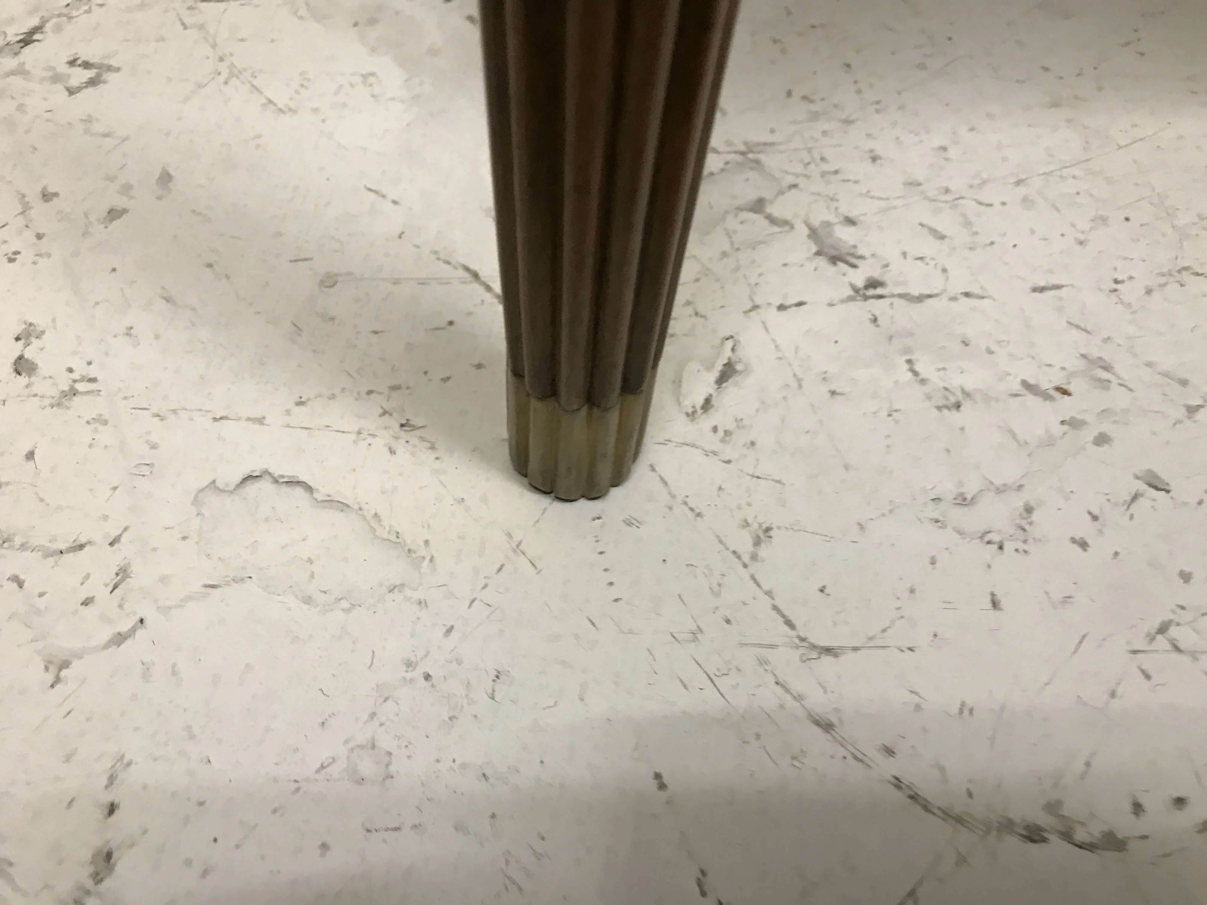 Une petite table antique avec des pieds délicats dans un cadre neutre.