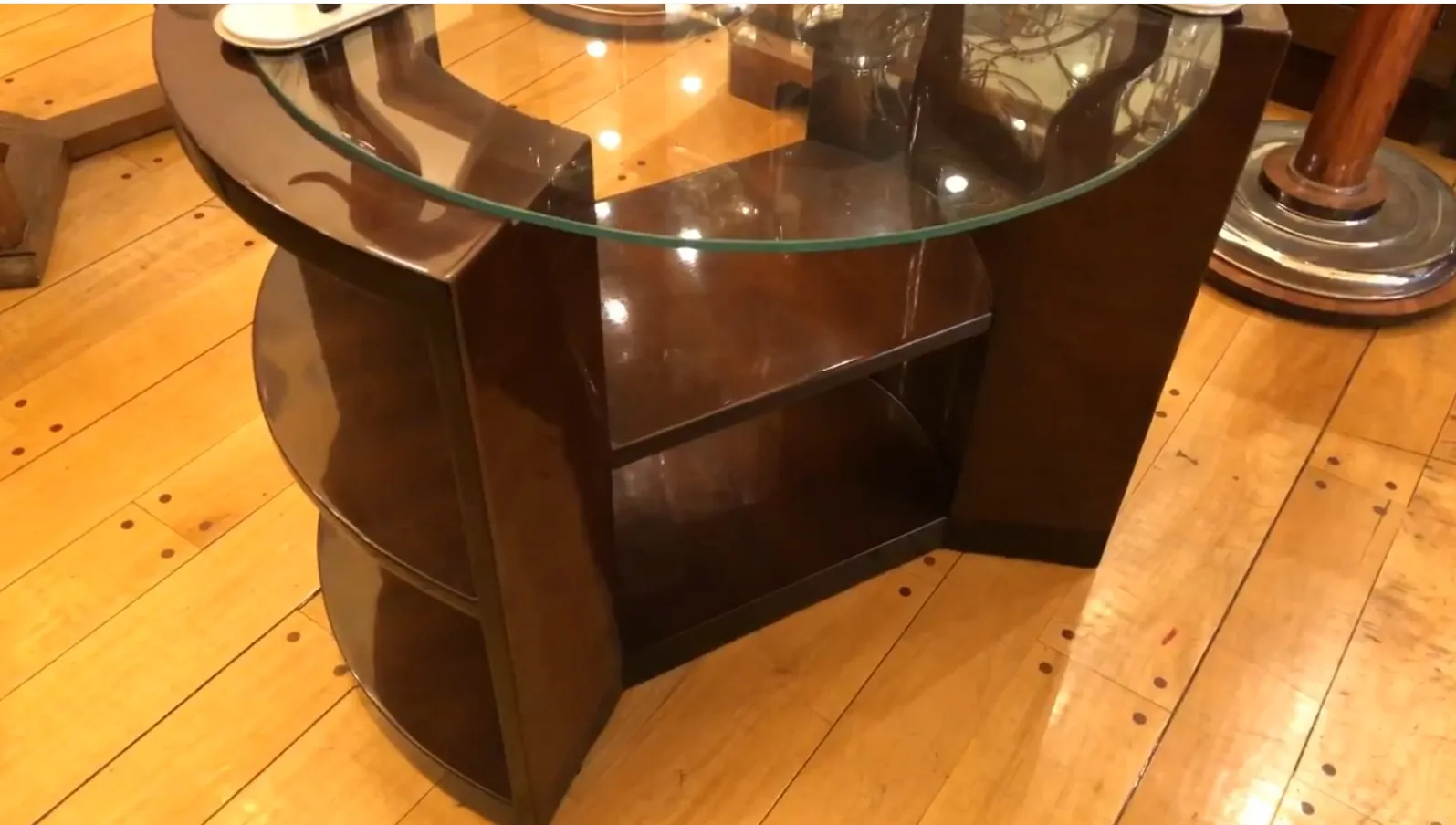 Mesa antigua de estilo Art Deco con estantes y forma curva.