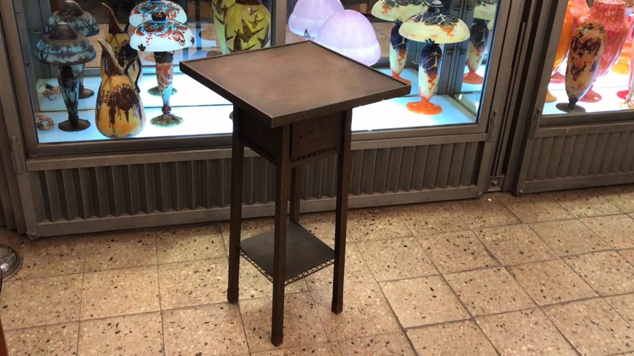 Mesinha antiga pequena com detalhes decorativos, em um ambiente de antigüidades.