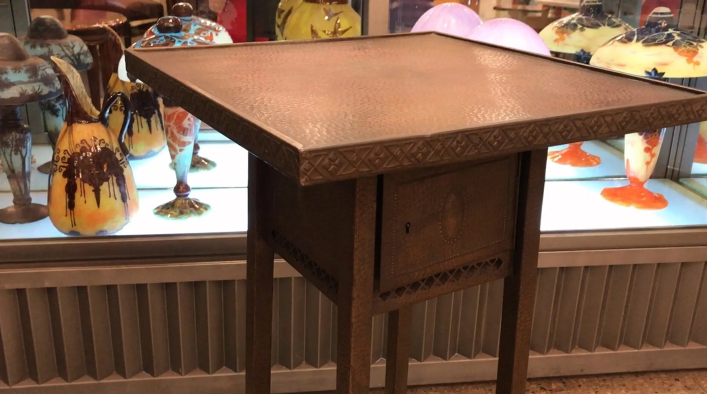 antiker kleiner Tisch mit filigranem Design und bunten Vasen im Hintergrund