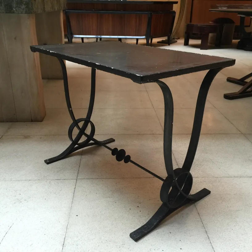 Mesa antiga Art Deco com design elegante e curvo em um ambiente sólido.