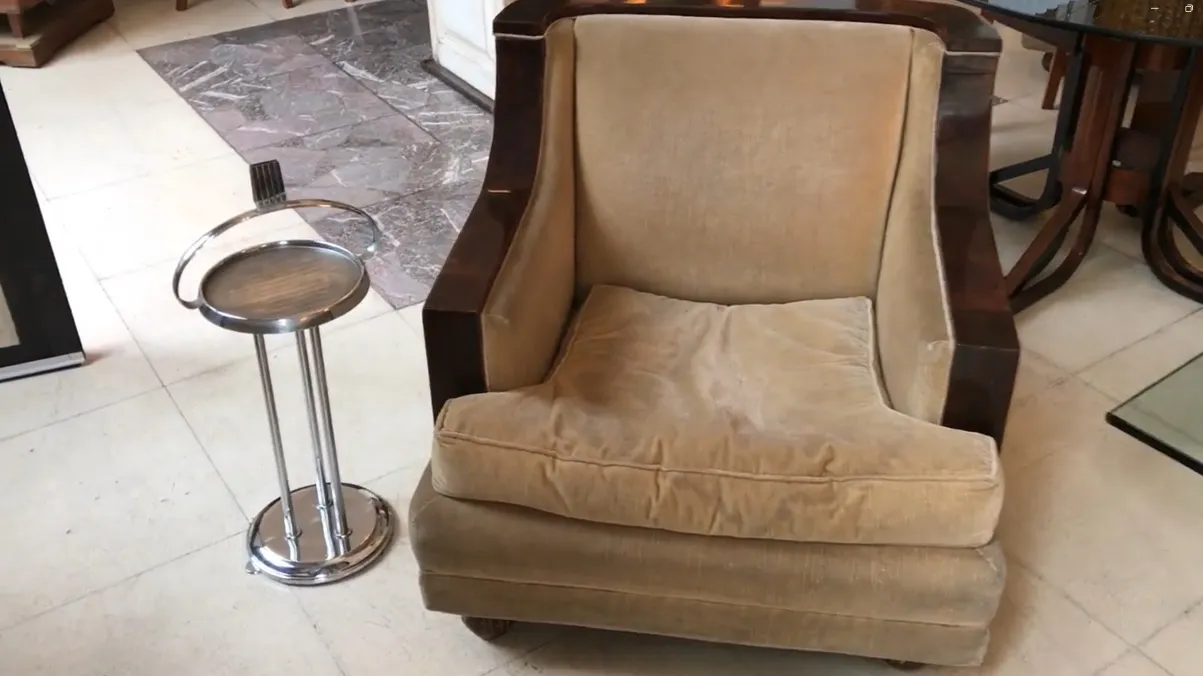 Tavolino antico con design elegante e spazio funzionale accanto a una poltrona.