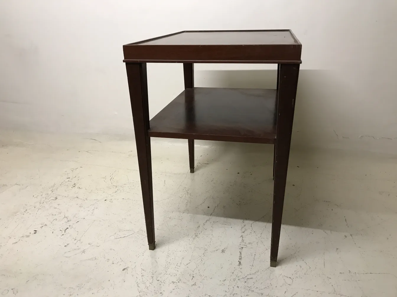 Tavolo antico in stile Art Deco con mensola inferiore in un ambiente semplice.