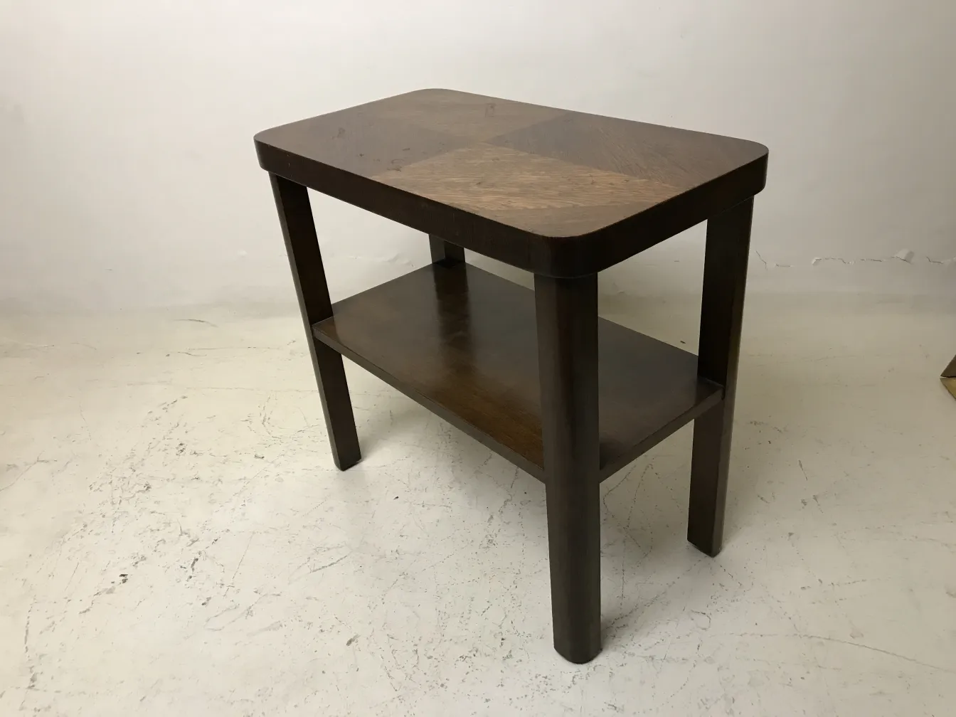 mesa antiga com prateleira inferior em um ambiente neutro