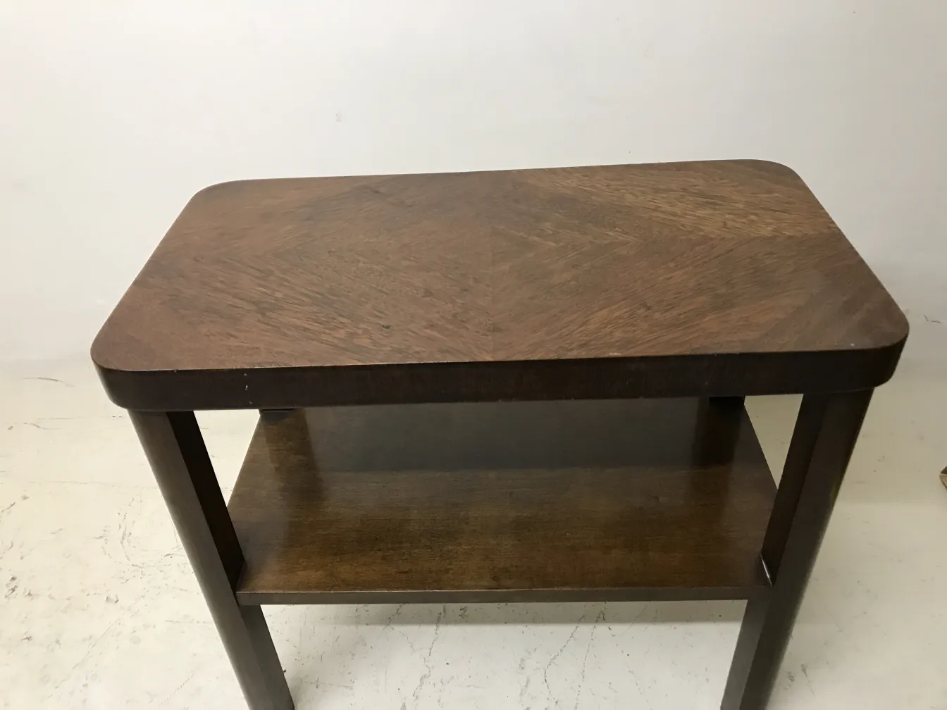 antique art deco table with a lower shelf, elegant design, featuring smooth finish and straight shapes, set against a neutral background.