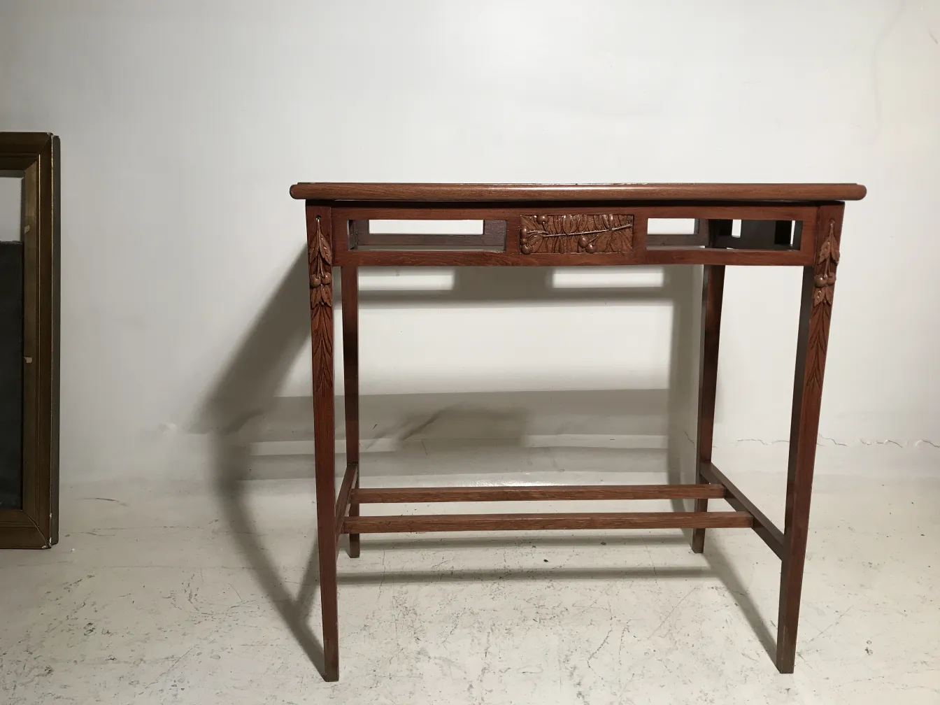 Tavolo antico in stile Art Nouveau con dettagli decorativi su sfondo neutro