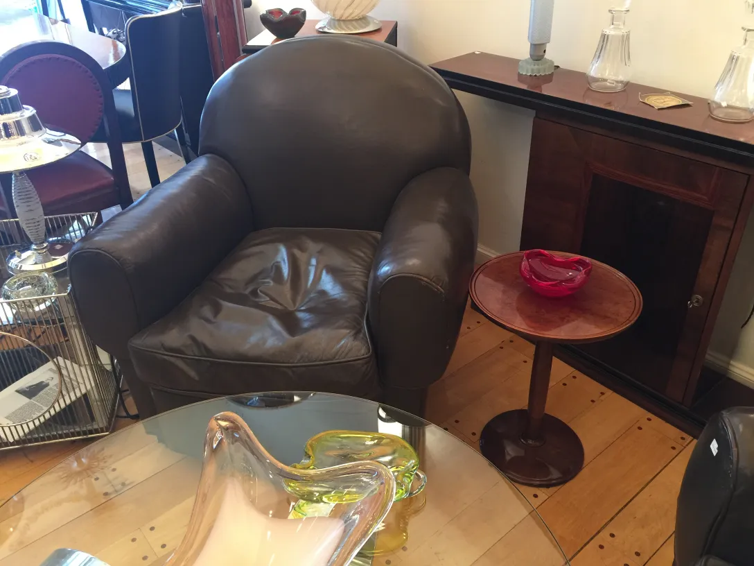small table with a classic design next to a leather chair. Cozy and antique surroundings.