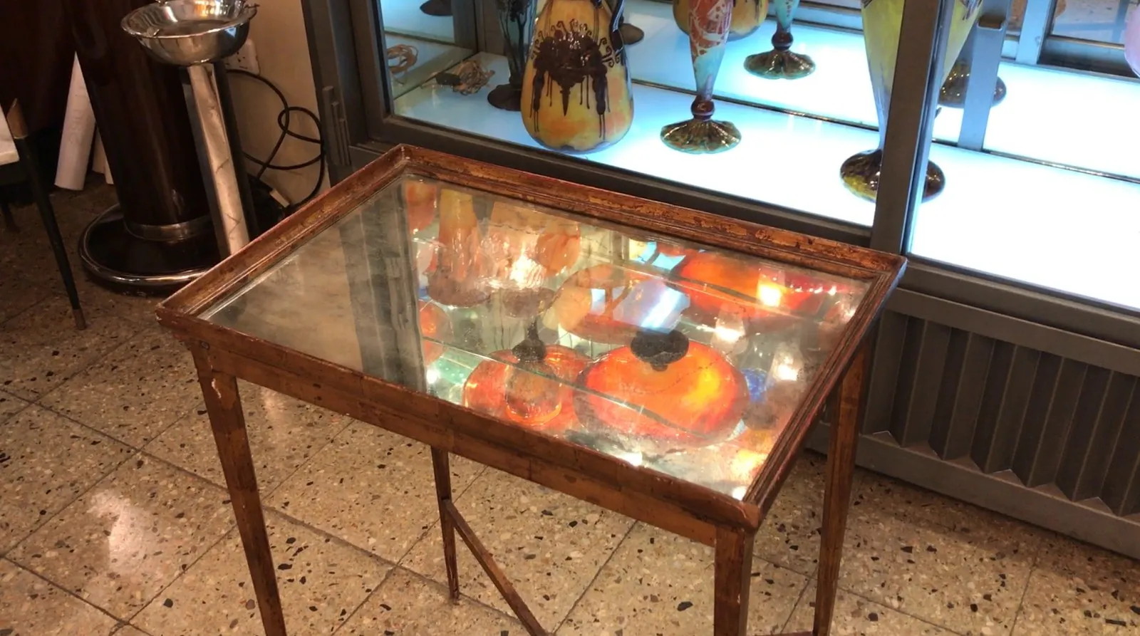 Tavolo antico con piano in vetro in un ambiente vintage, circondato da decorazioni