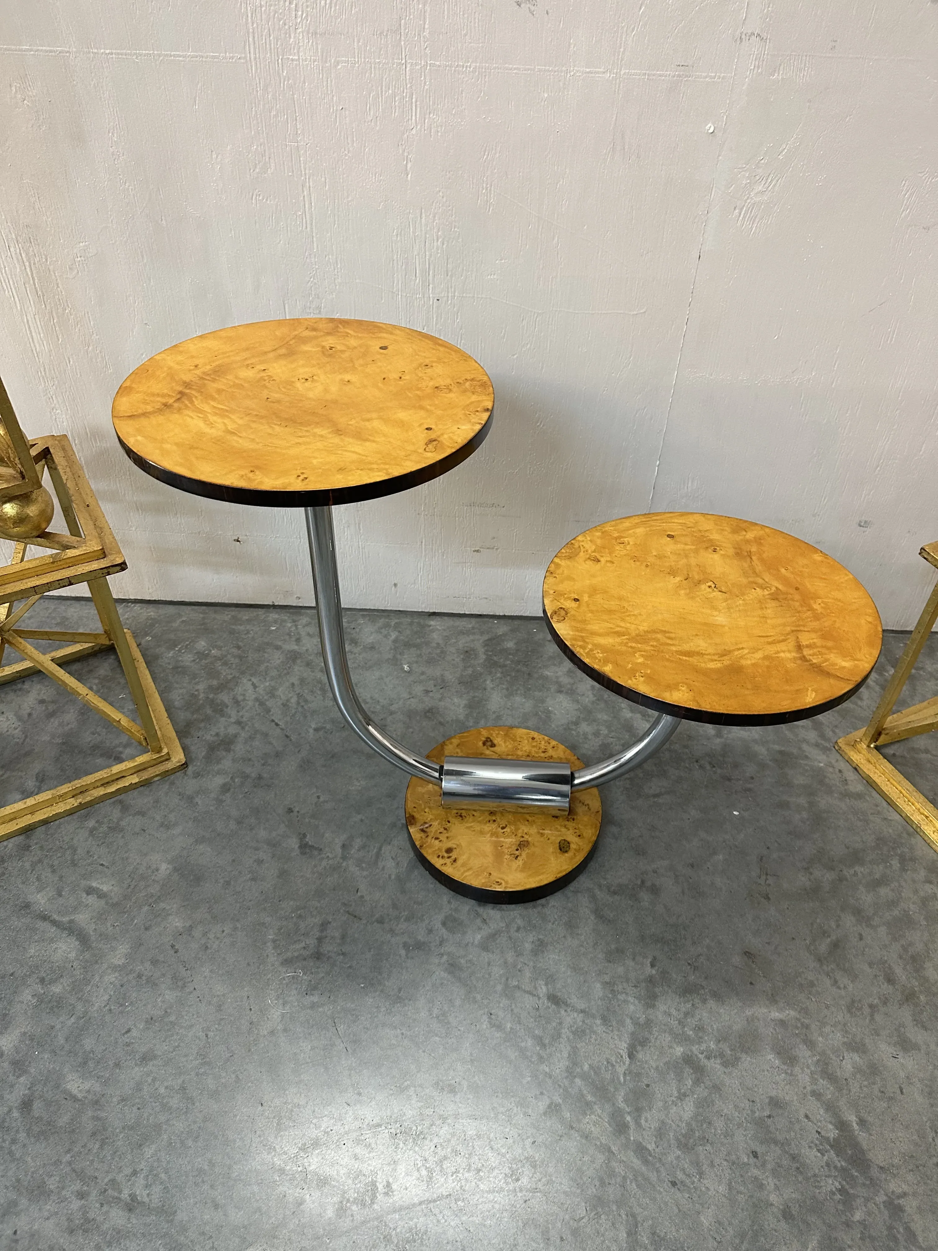 Antiker kleiner Tisch mit zwei runden Oberflächen und Metallbasis in einer modernen Umgebung.