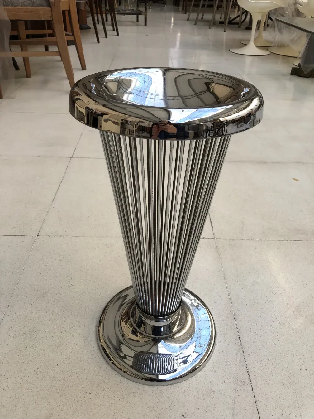 Antique standing ashtray with a shiny design, set in a modern interior.