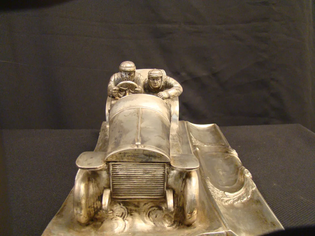 antique inkwell shaped like a racing car with two drivers, shiny metal details